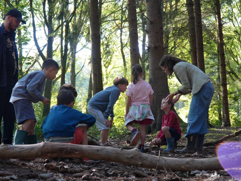 Des élèves observent le sol de la forêt avec deux adultes