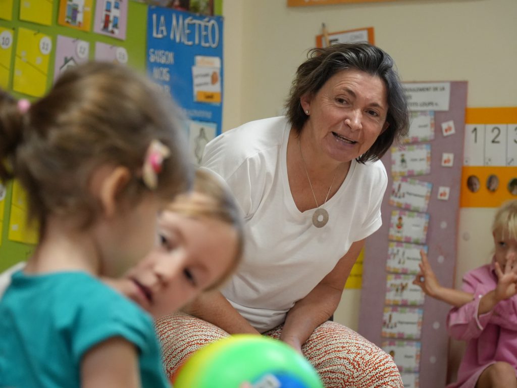 Une enseignante de maternelle sourit aux enfants pendant une activité en classe
