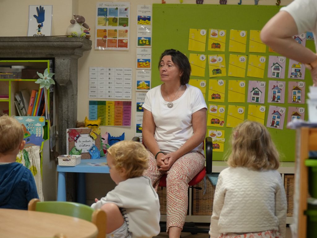En classe maternelle, l'enseignante et les enfants réunis en cercle