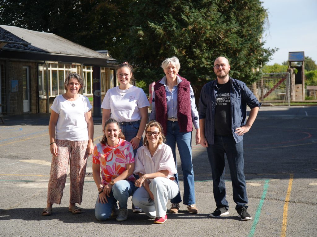 L'équipe de l'école réunie dans la cour de récréation, devant les bâtiments